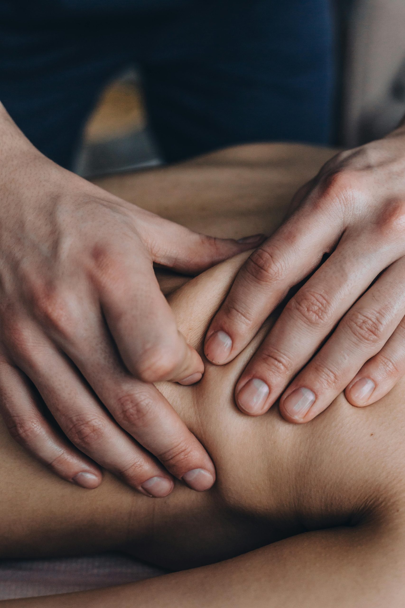 Close-up of hands giving a therapeutic massage on a person's shoulder, promoting relaxation.